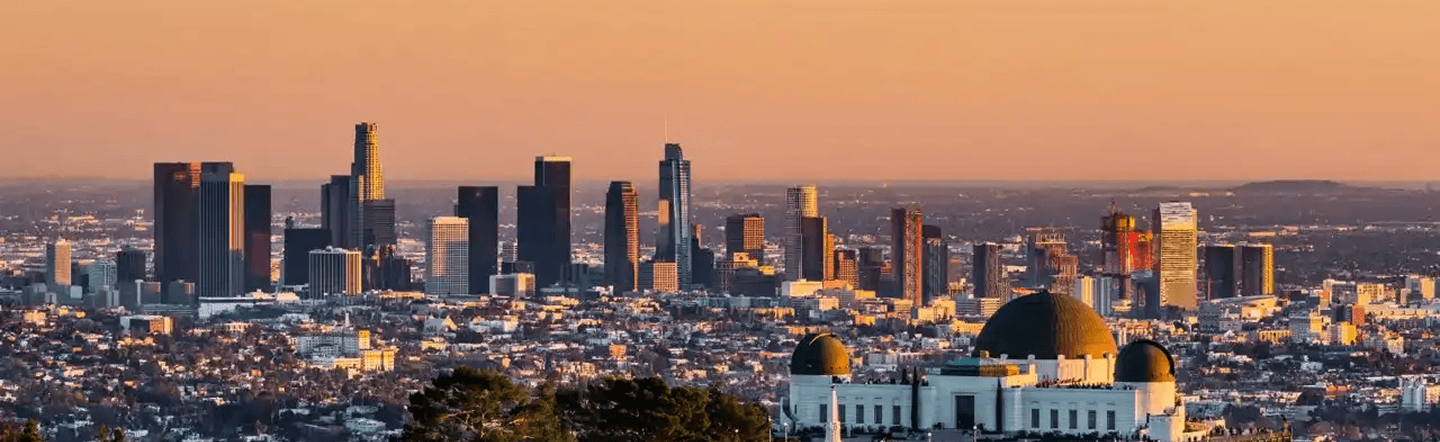 Panoramic view of the Southern California skyline at sunset, featuring Griffith Observatory overlooking the city