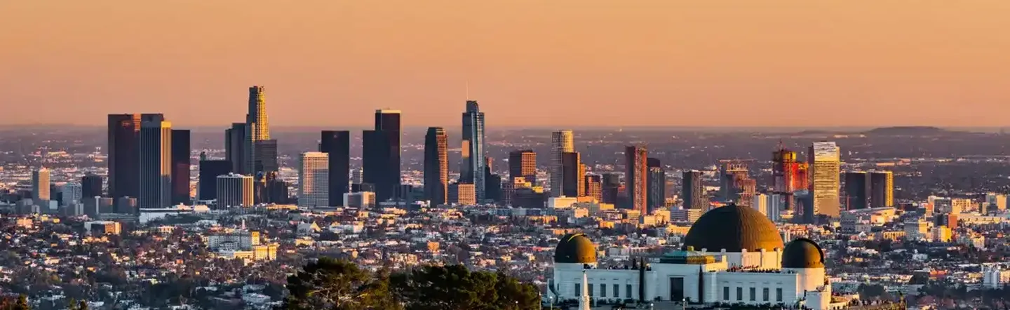 Panoramic view of the Southern California skyline at sunset, featuring Griffith Observatory overlooking the city